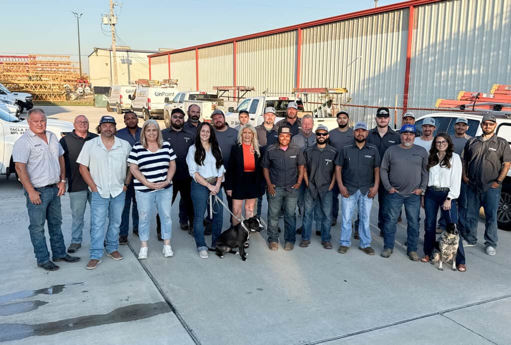OnPoint Mechanical team group photo outdoors with employees and dogs, industrial background, sunny d.
