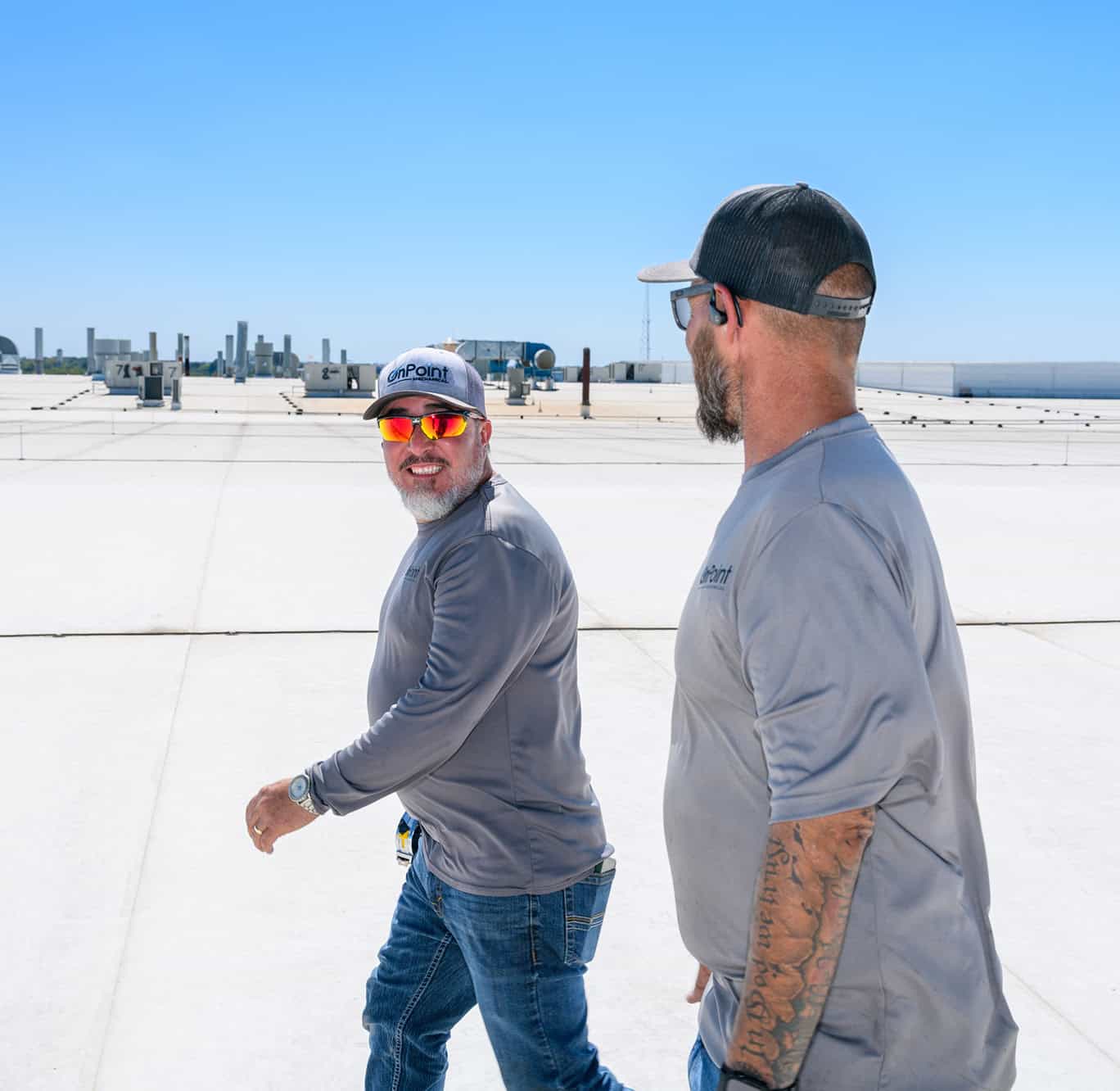 ACME rooftop HVAC technicians inspecting equipment on a sunny day.