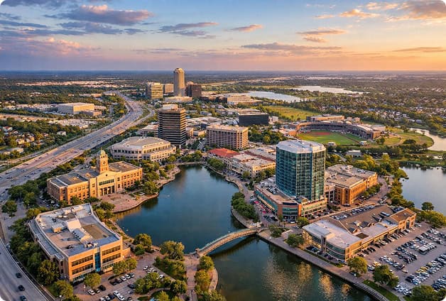Aerial view of downtown city with water bodies and modern buildings at sunset.